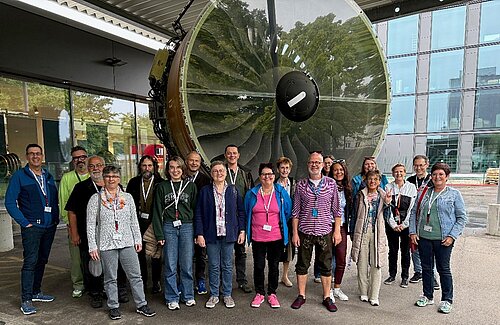 Ein Gruppenbild der DAWG-Mitarbeiter vor einem großen Flugzeug-Triebwerk