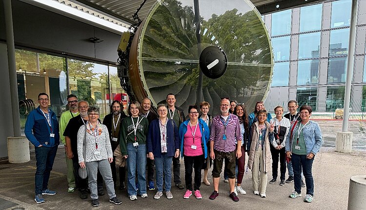 Ein Gruppenbild der DAWG-Mitarbeiter vor einem großen Flugzeug-Triebwerk